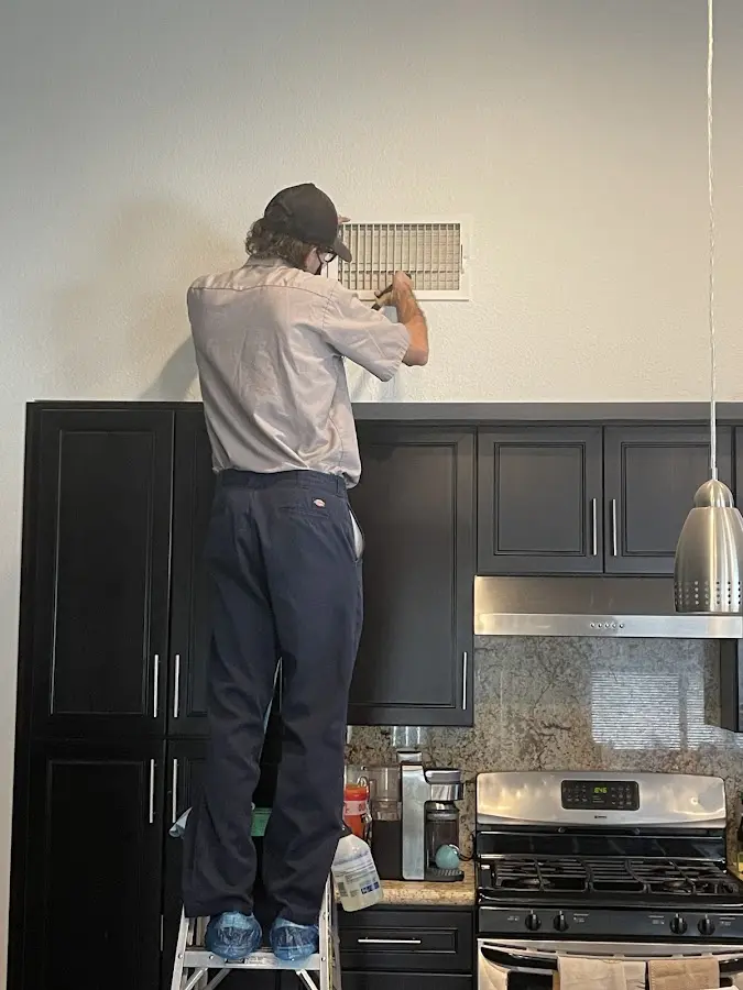 Technician inspecting an air vent during HVAC service in Oakwood